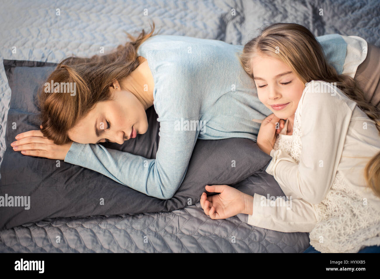 Она лежит как маме. Мама с дочкой лежат на кровати. Мама и дочь валяются в кровати. Дочка лежит на маме. Дочь ледижит на кровати.