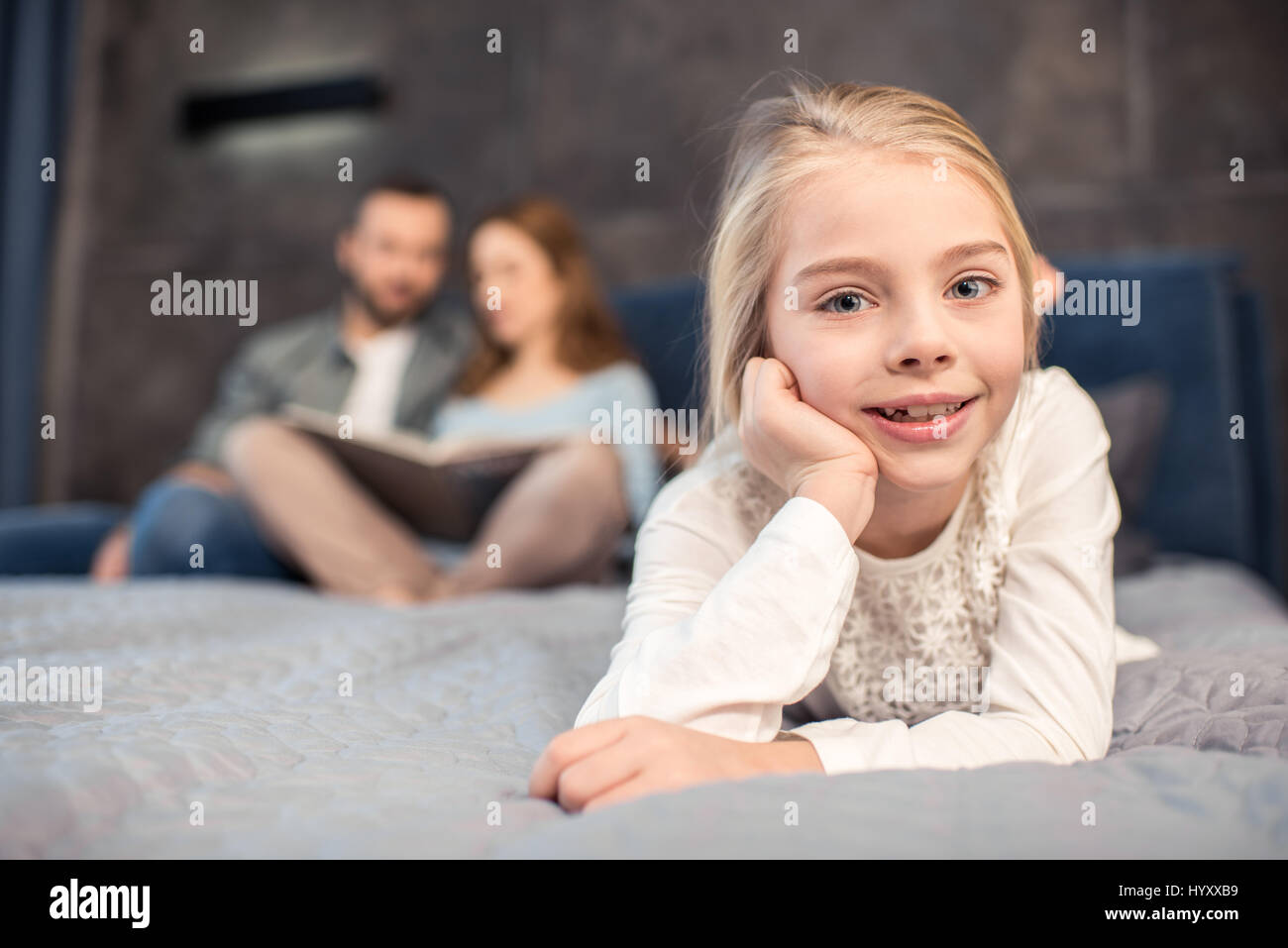 Beautiful preteen girl lying on bed and smiling at camera Stock Photo ...