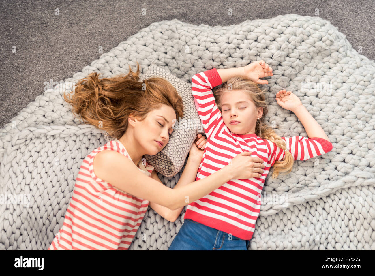 Top view of mother and daughter lying on wool blanket and sleeping ...