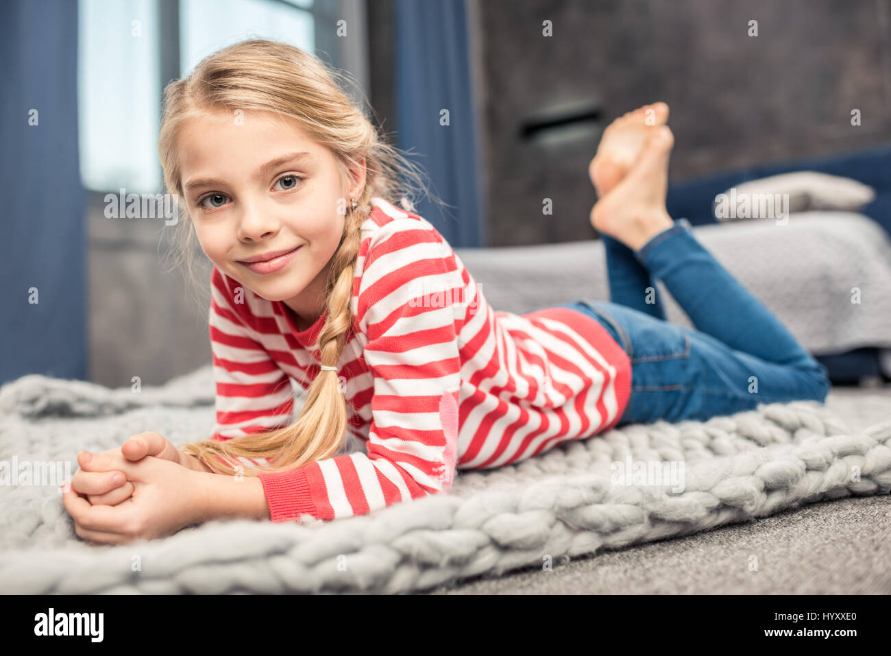 Pretty little girl lying on floor and smiling at camera Stock Photo - Alamy