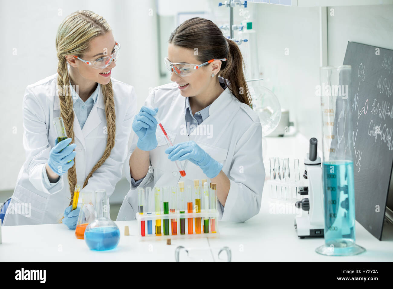 Two young female scientists making experiment in chemical laboratory ...