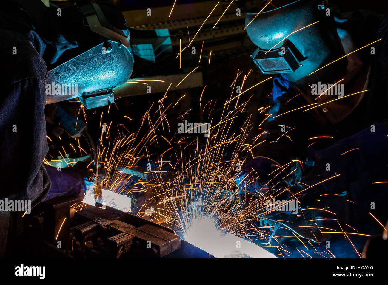 worker with protective mask welding metal in automotive assembly factory. Stock Photo