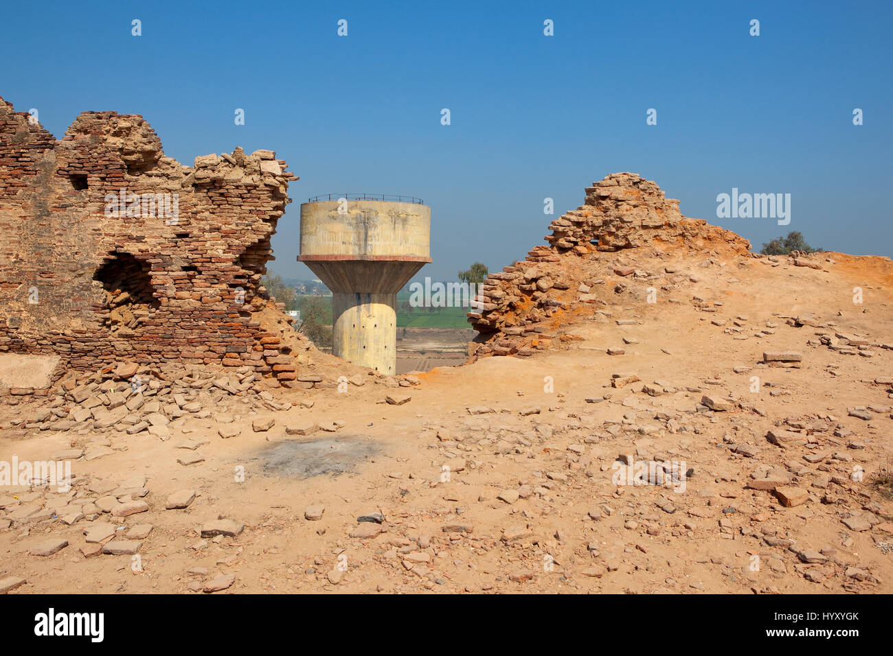 bhatner fort walls in need of restoration work with a water tower in hanumangarh rajasthan india under a blue sky Stock Photo