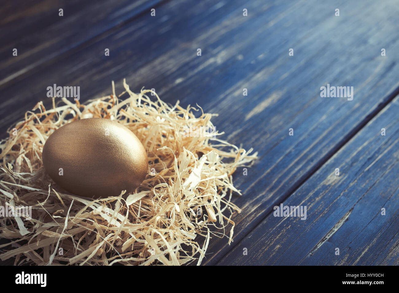 Golden egg in a nest on an old wooden table Stock Photo - Alamy