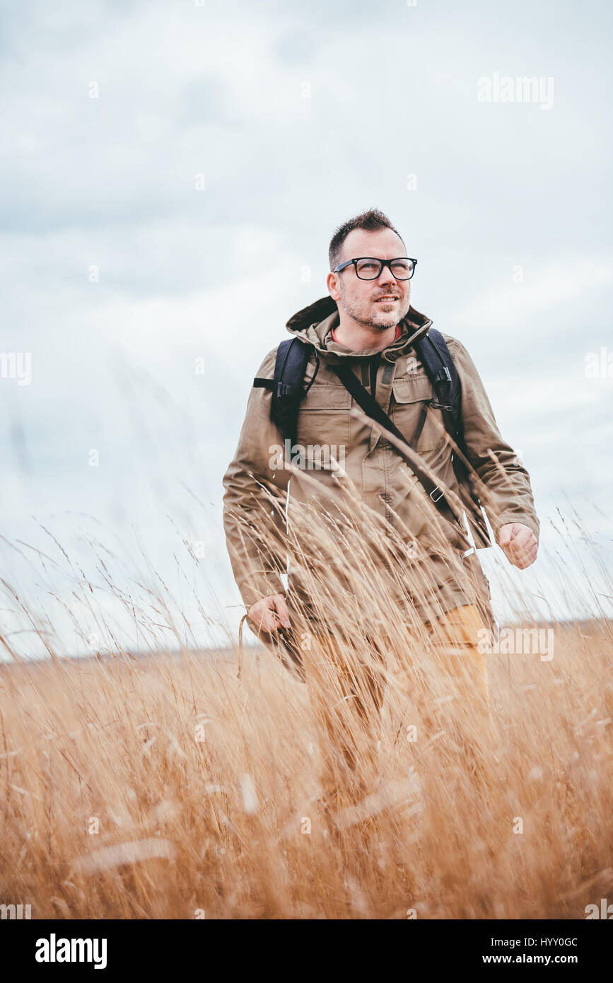 Hiker walking in high grass and looking at the distance Stock Photo