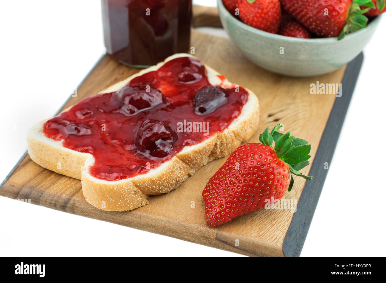 Bread with strawberry jam on a wooden board. Tasty breakfast , Ripe strawberries isolated on white background. Stock Photo