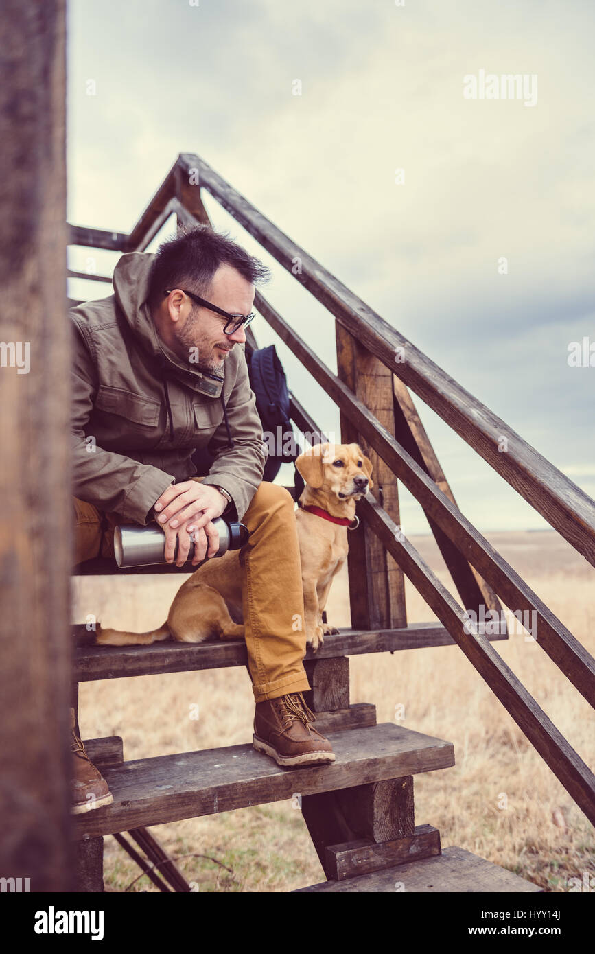 Hiker and dog sitting on the stairs of hikers rest cabin Stock Photo