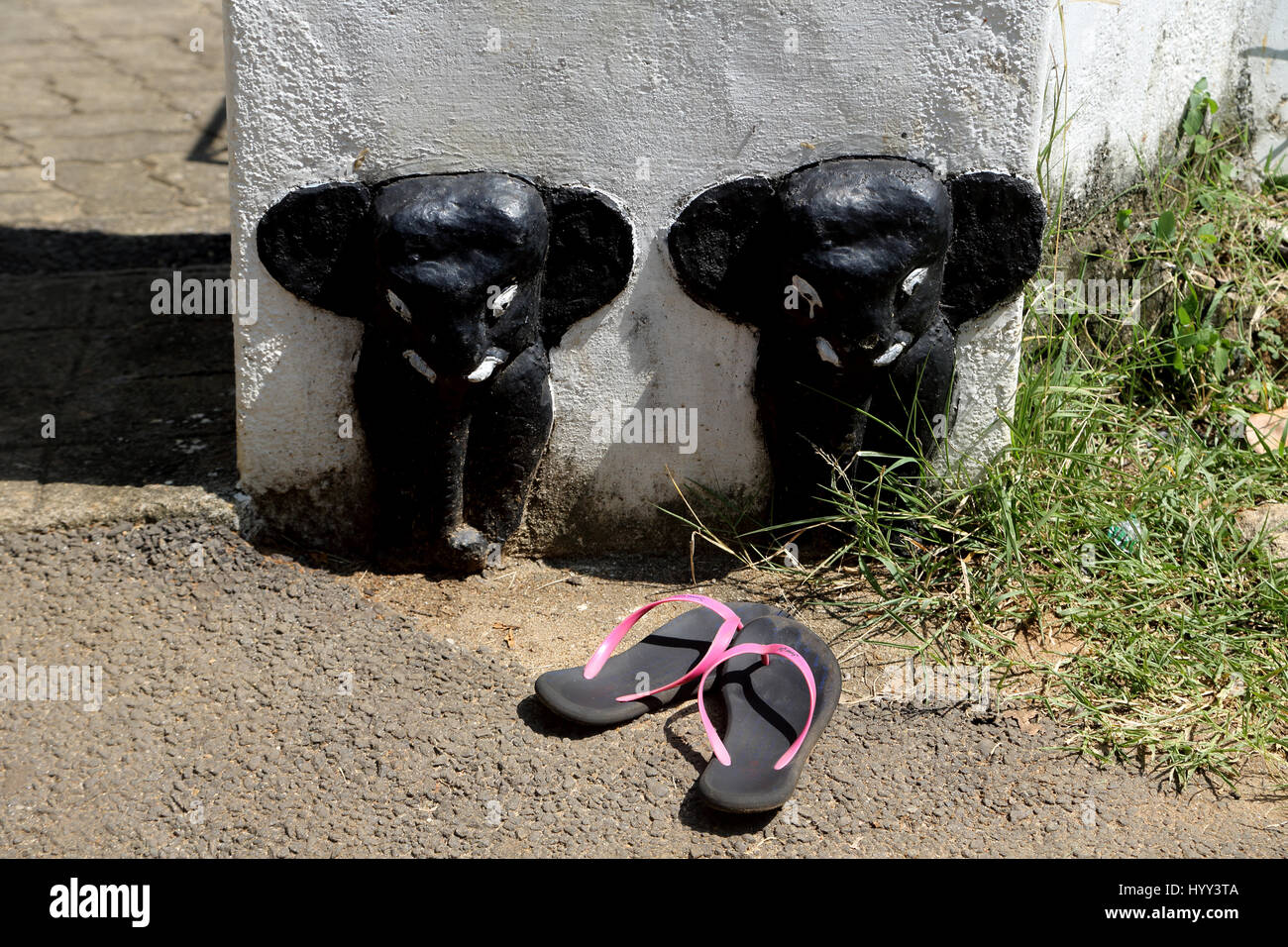 Aluviharaya Rock Cave Temple Sri Lanka Matale District Kandy-Dambulla Highway A Pair Of Flip Flops Infront Of Carved Elephants on Wall outside Dagoba Stock Photo