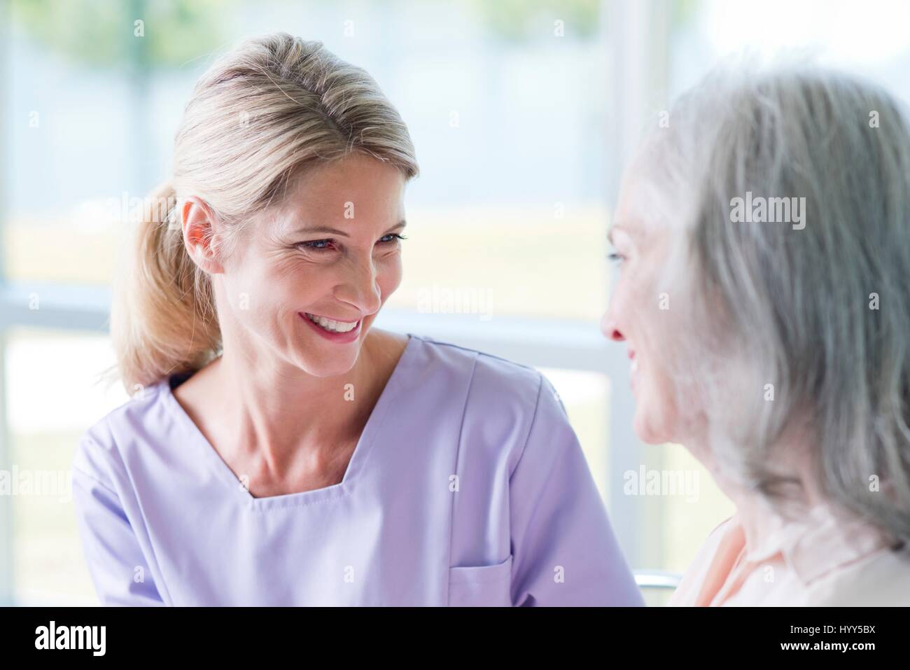 Senior woman and mature woman smiling towards each other. Stock Photo