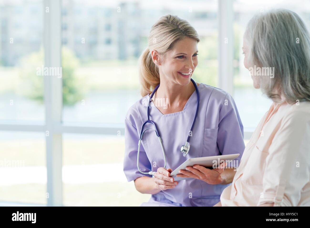 Senior woman and care worker smiling towards each other. Stock Photo