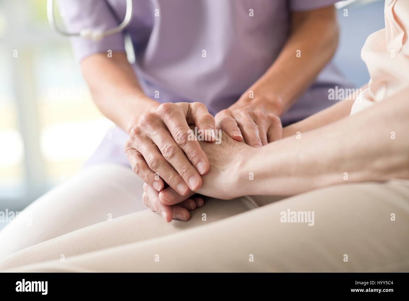 Care worker holding senior woman's hands. Stock Photo