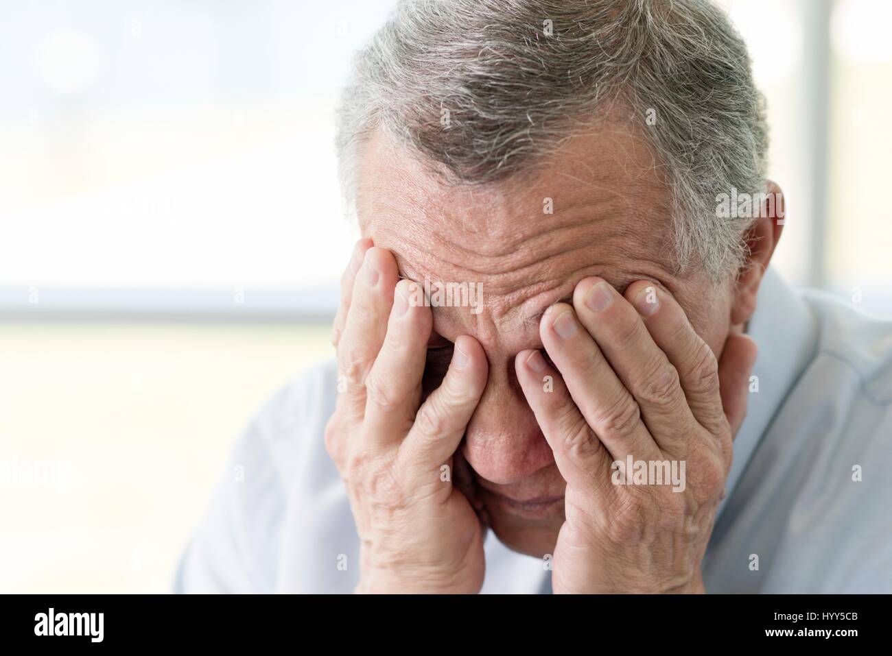 Senior man with hands covering face, close up. Stock Photo