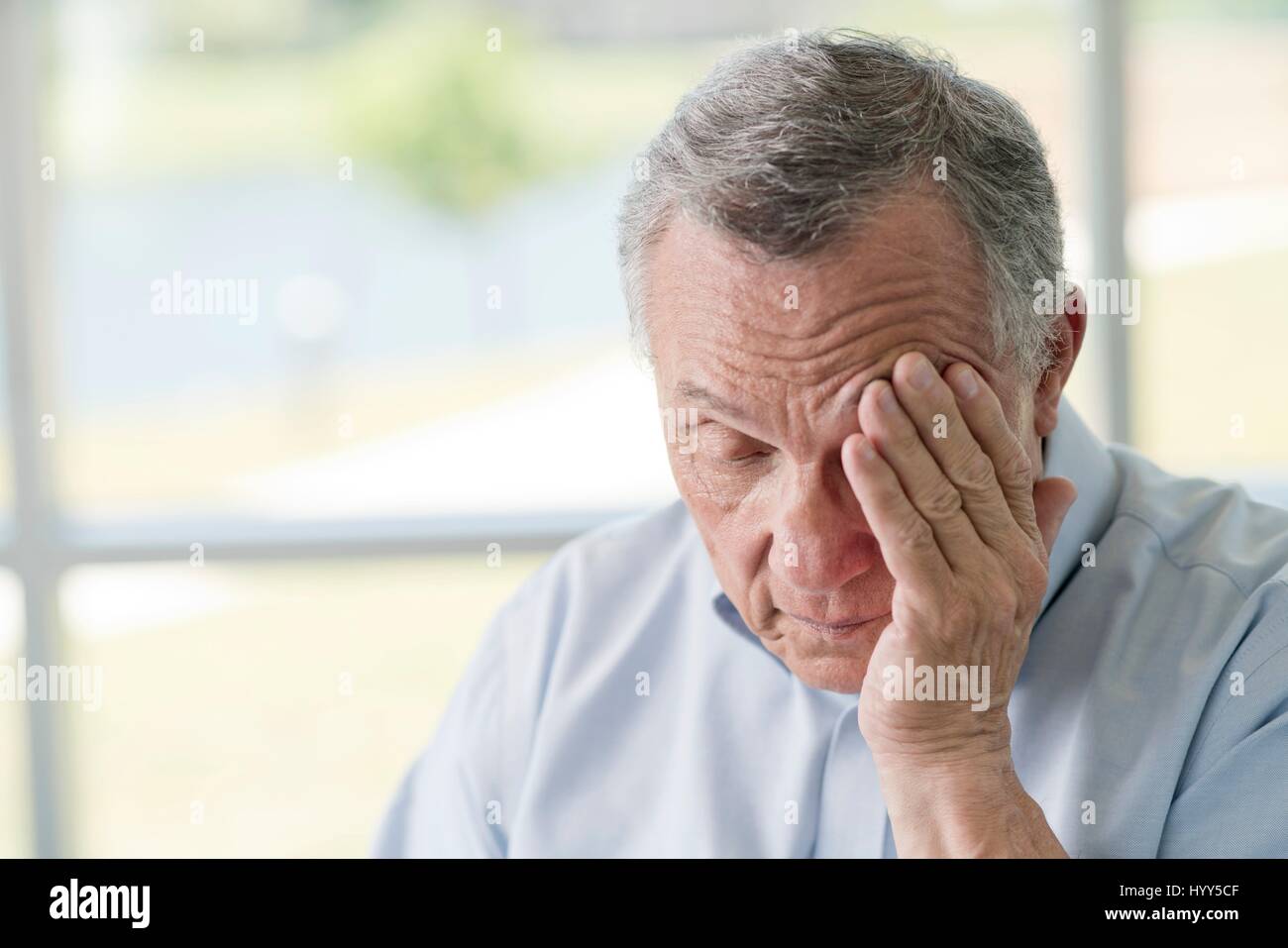 Senior man rubbing face. Stock Photo