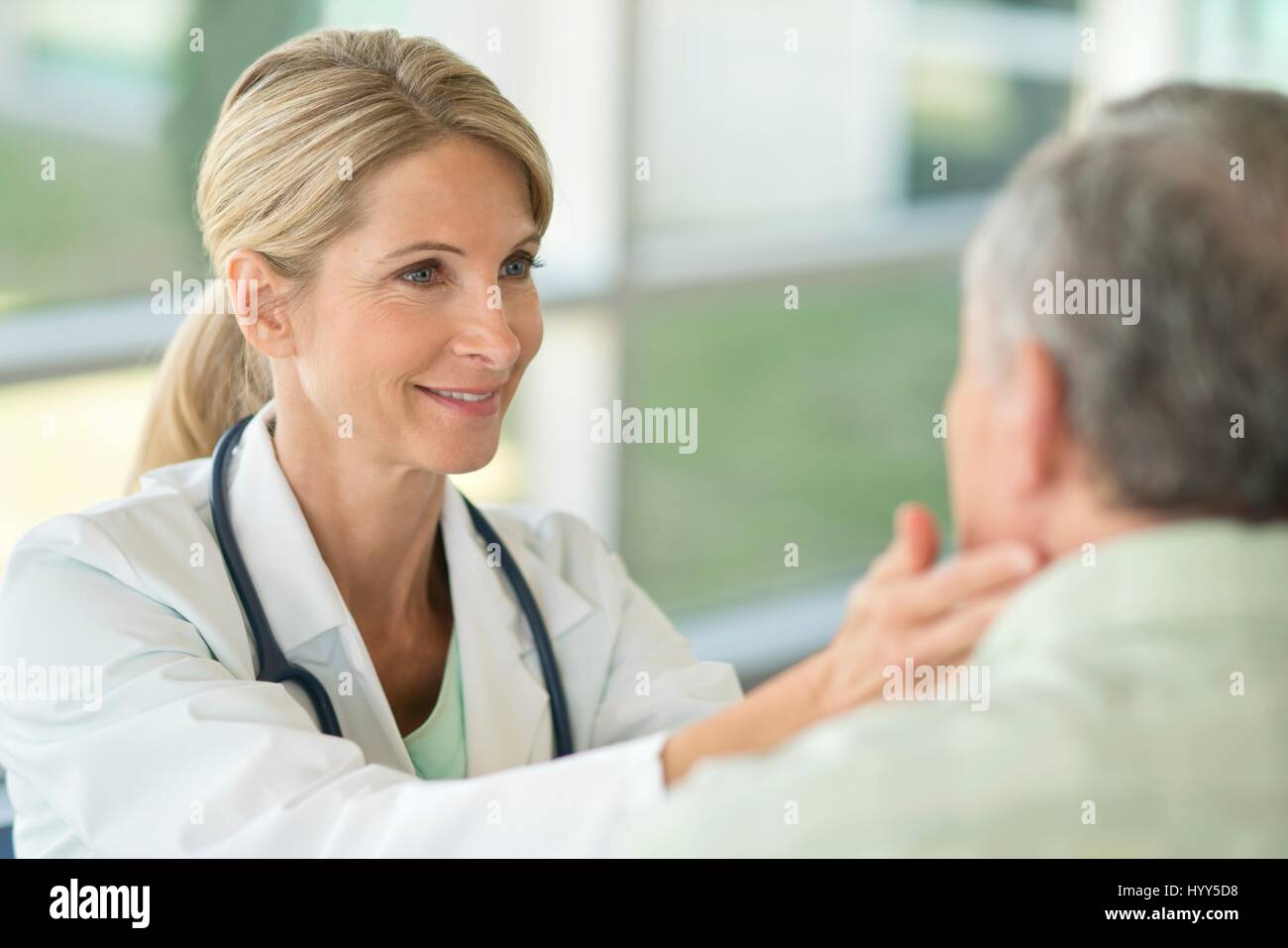 Female doctor touching senior man's neck. Stock Photo