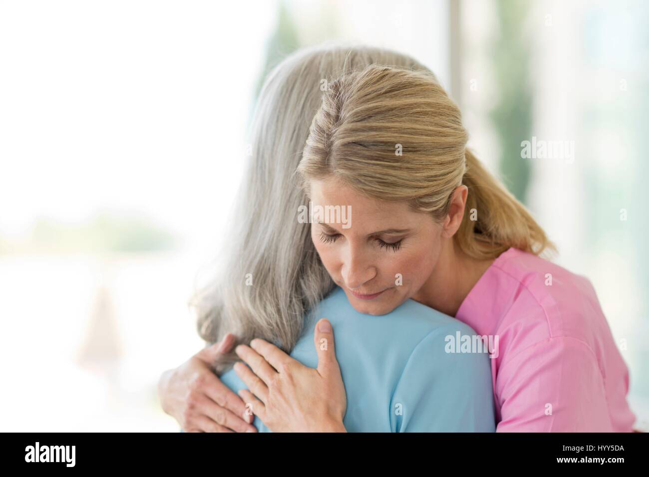 Female care worker embracing female patient. Stock Photo