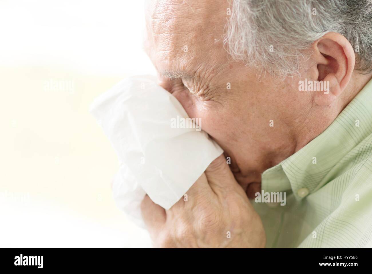 Senior man blowing nose on tissue. Stock Photo
