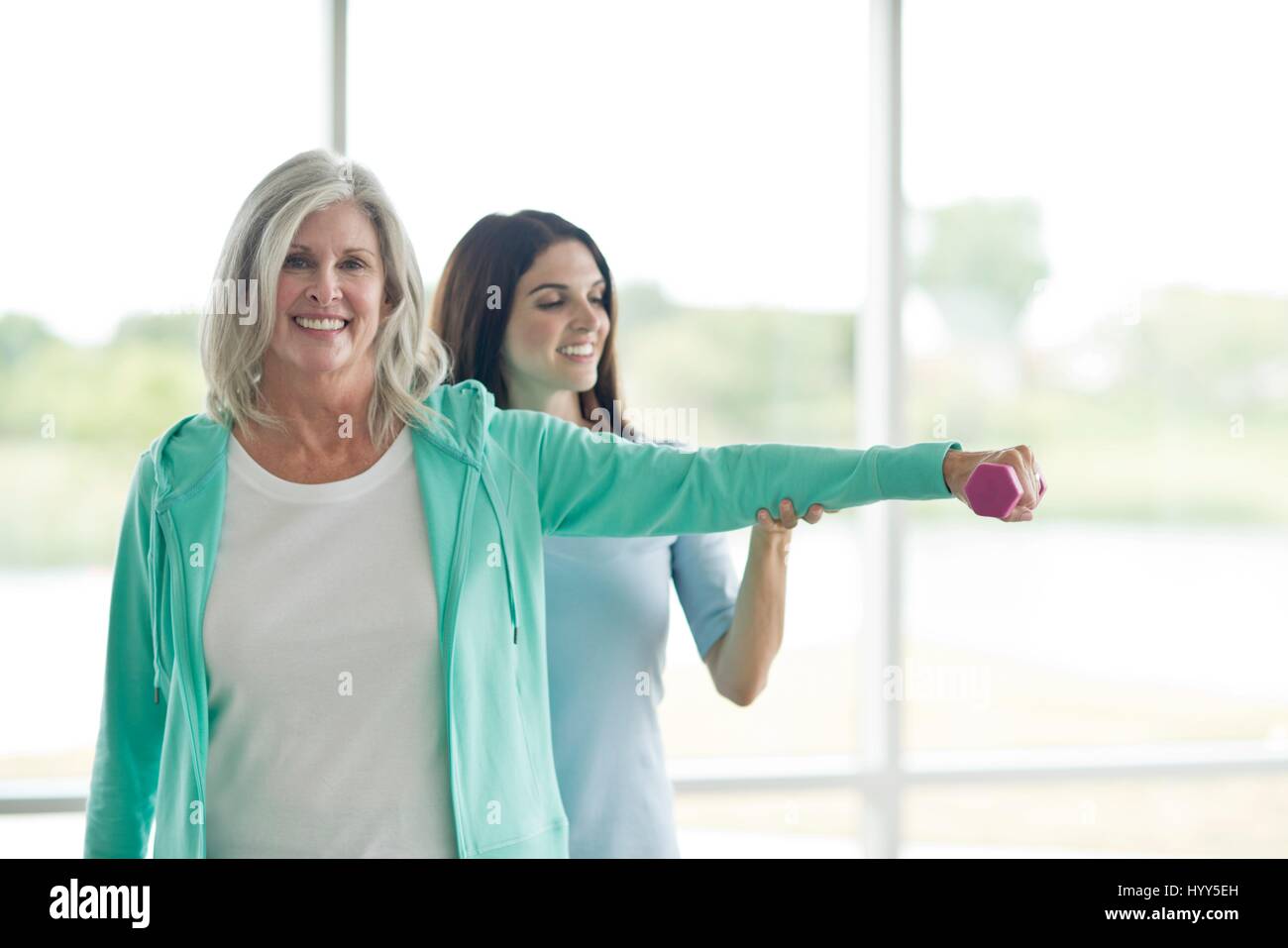 Senior woman using hand weight with personal trainer. Stock Photo