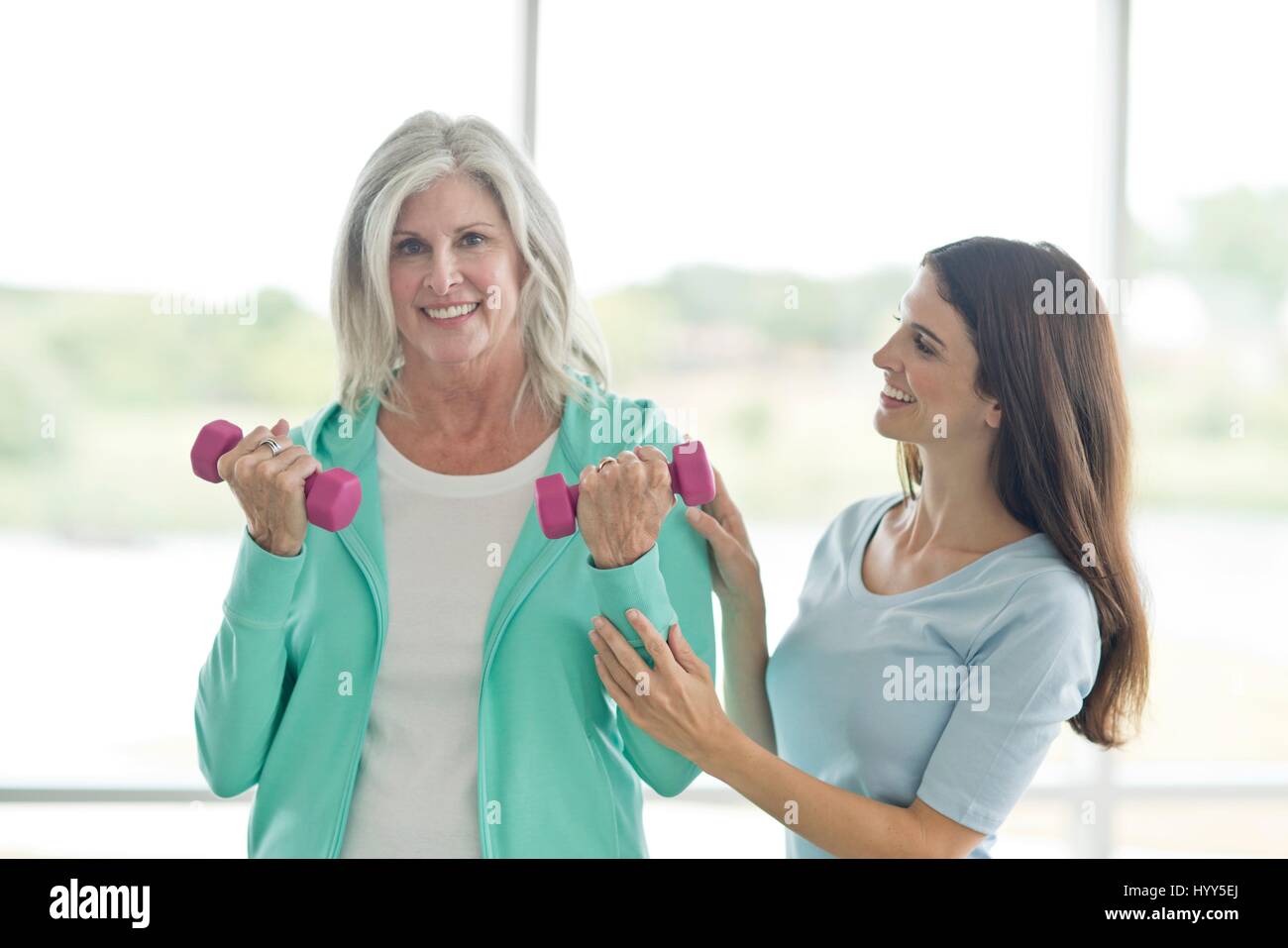 Senior woman using hand weights with personal trainer. Stock Photo