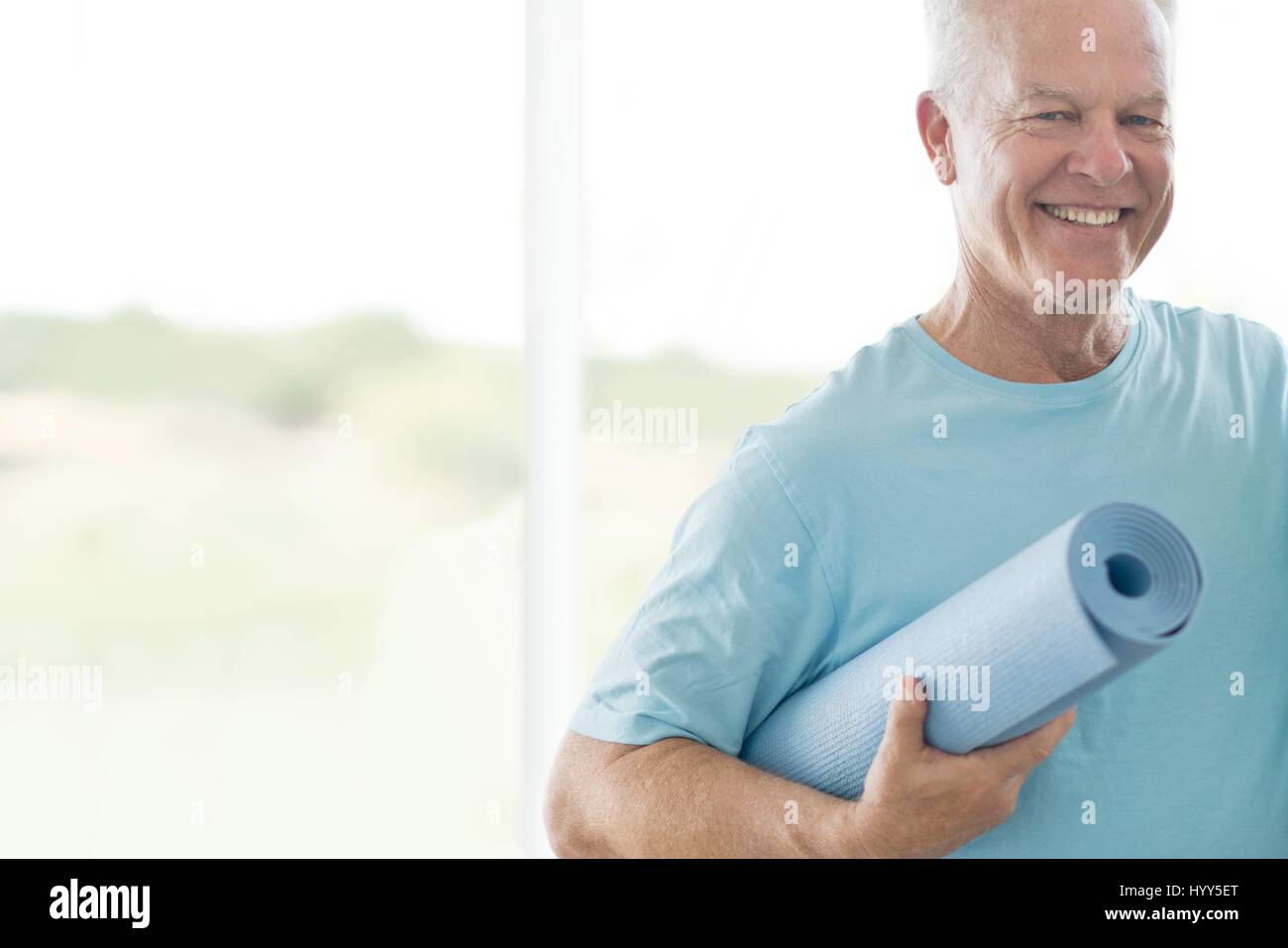 Senior man holding yoga mat. Stock Photo