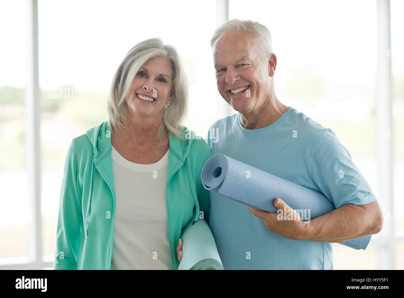 Senior couple holding yoga mats. Stock Photo