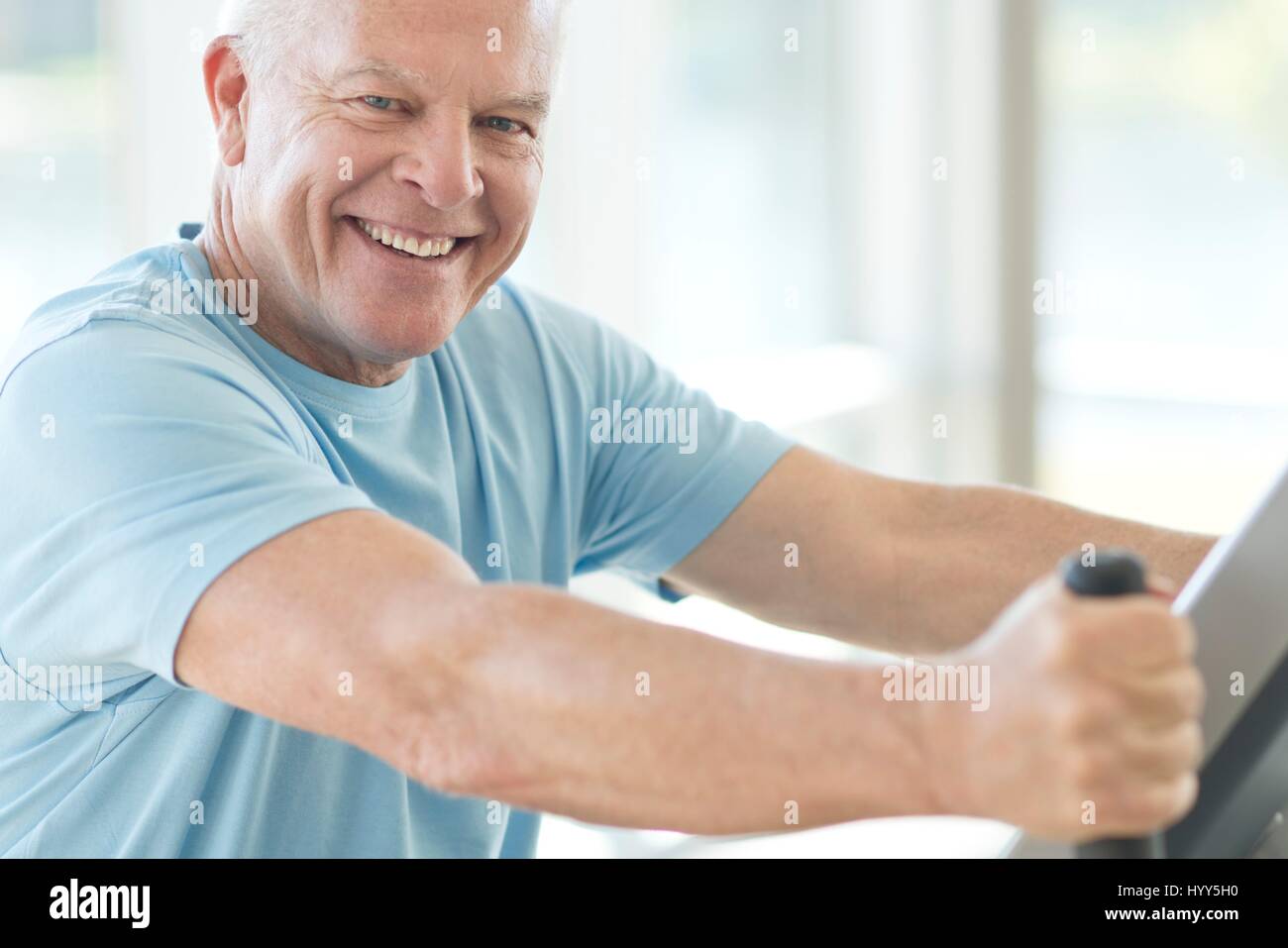 Senior man on static bike in the gym. Stock Photo