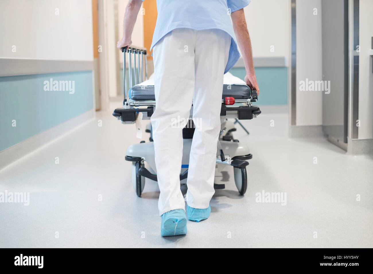 Nurse orderly pushing bed down corridor. Stock Photo