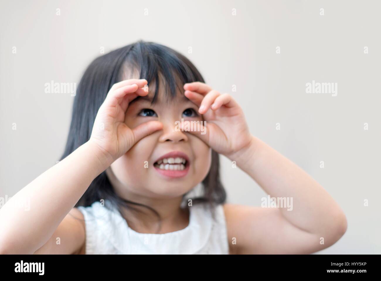 Young girl with finger round eyes, studio shot. Stock Photo