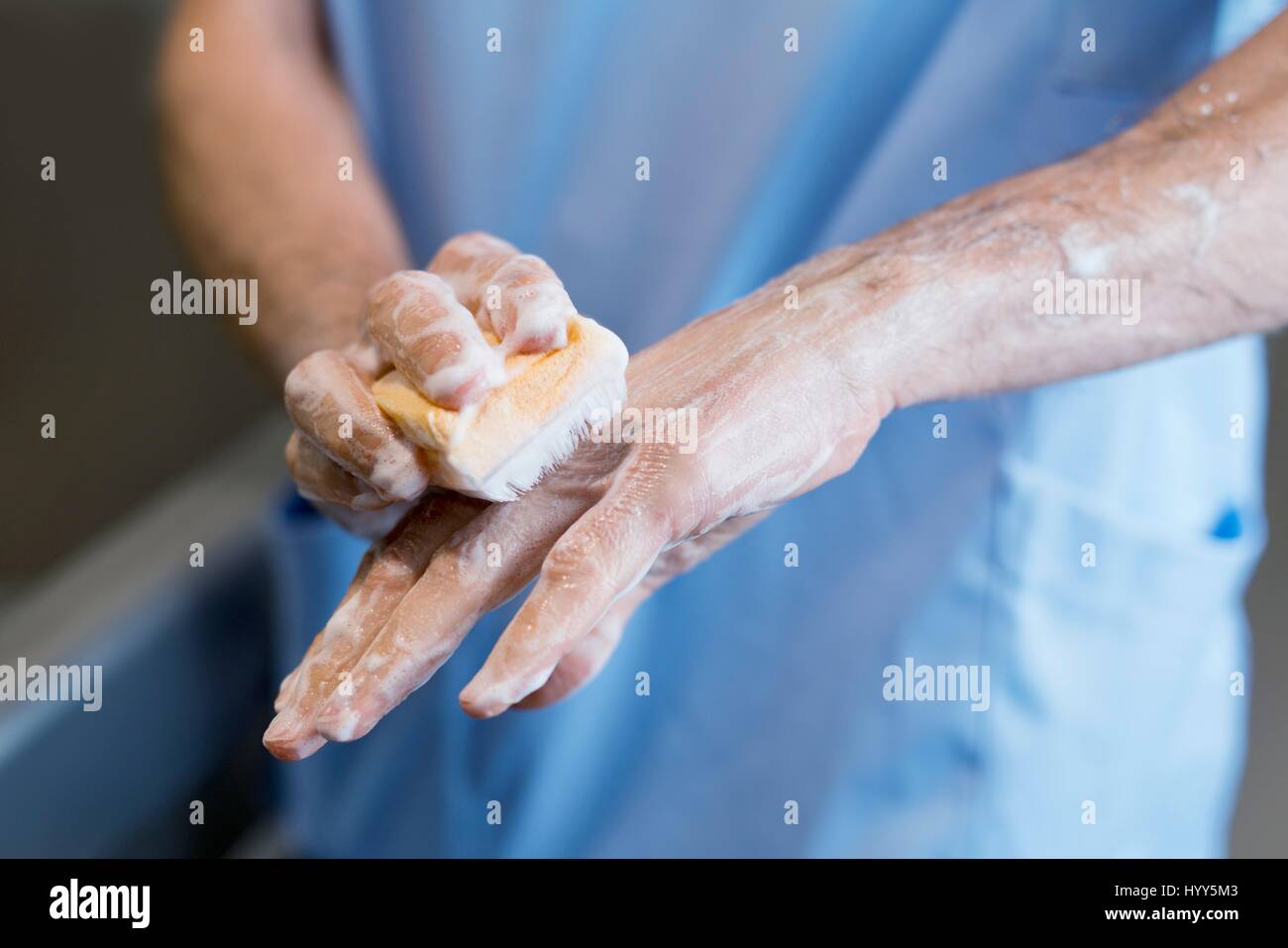 Doctor scrubbing hands with brush in hospital. Stock Photo