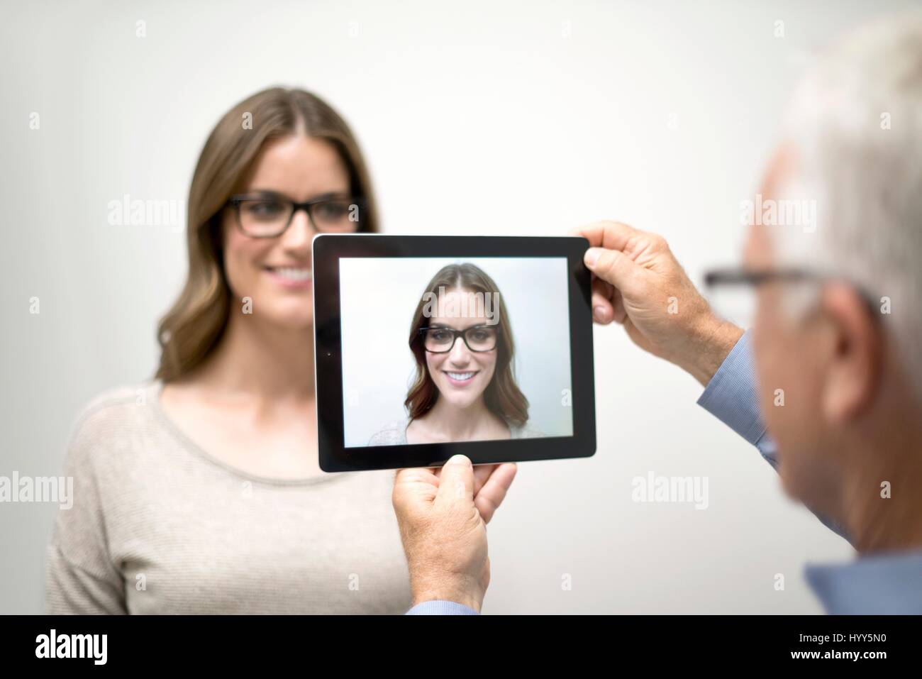 Man holding digital tablet in front of woman's face. Stock Photo