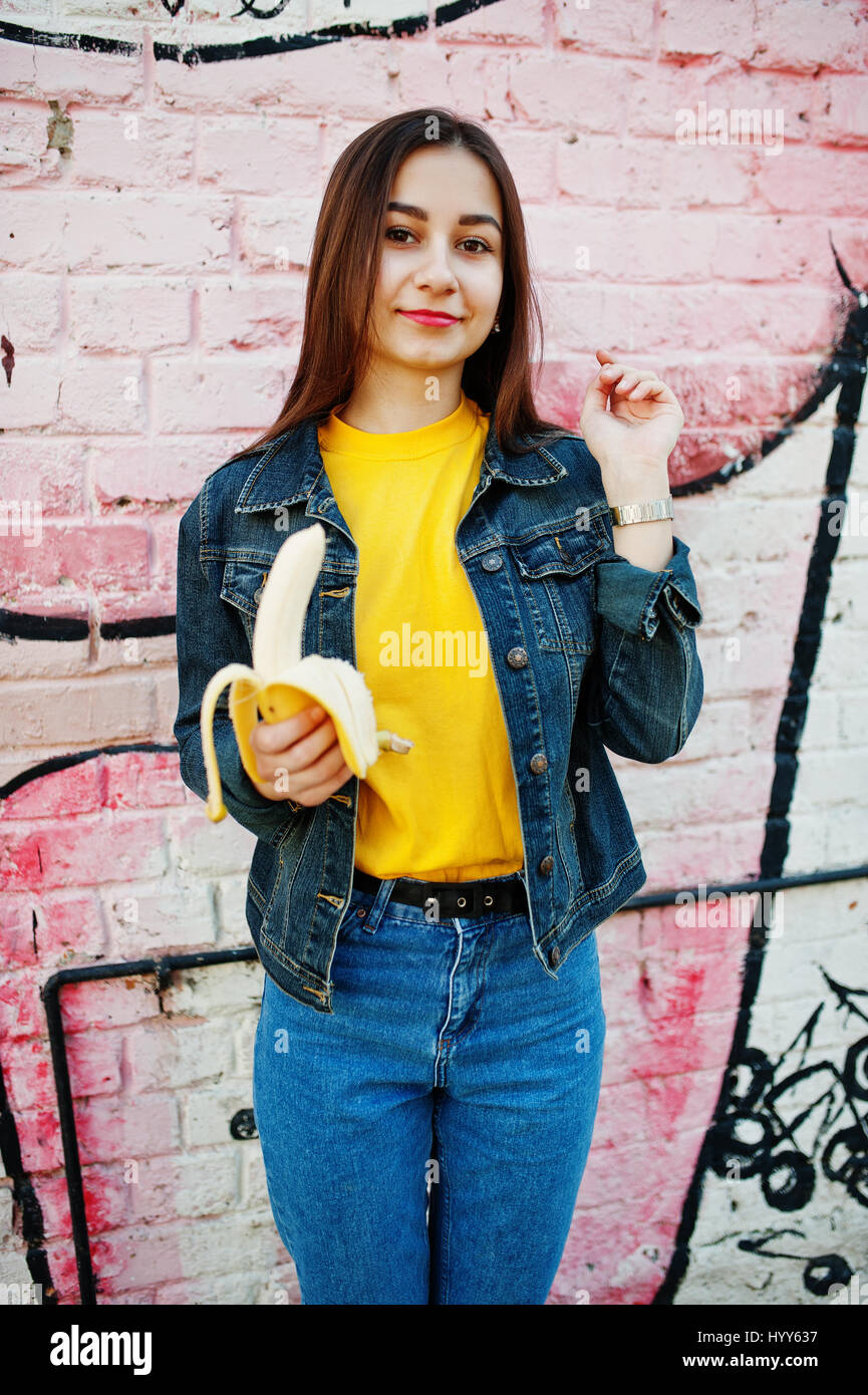 Beautiful teenage girl eat banana, wear yellow t-shirt, jeans near Stock  Photo - Alamy