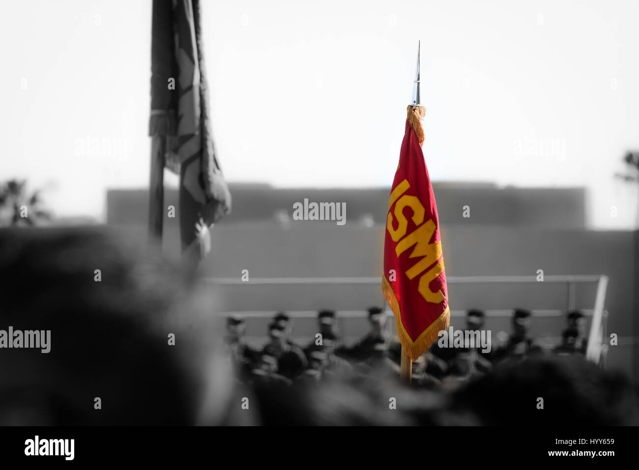 Flag displaying 'USMC' over a crowd of civilian and military watching the Battle Color Detachment perform at Marine Corps Recruit Depot San Diego, CA Stock Photo