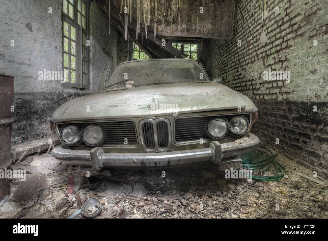 A BMW has been abandoned in a garage. STUNNING images reveal the vulnerable beauty of abandoned cars that have been left to rust over the years. The collection of spectacular images show how a Volkswagen Beetle, Citroën C2 and even a Ferrari have been taken over by nature and piles of rubble. In other shots, a Mercedes Benz is overgrown with ivy and an old-fashioned BMW has been left in a garage with a collapsing roof and debris on the floor. A Ford vehicle has also been forgotten in the woods and one car even appears to have a tree growing from it. The haunting images were taken by Belgian se Stock Photo