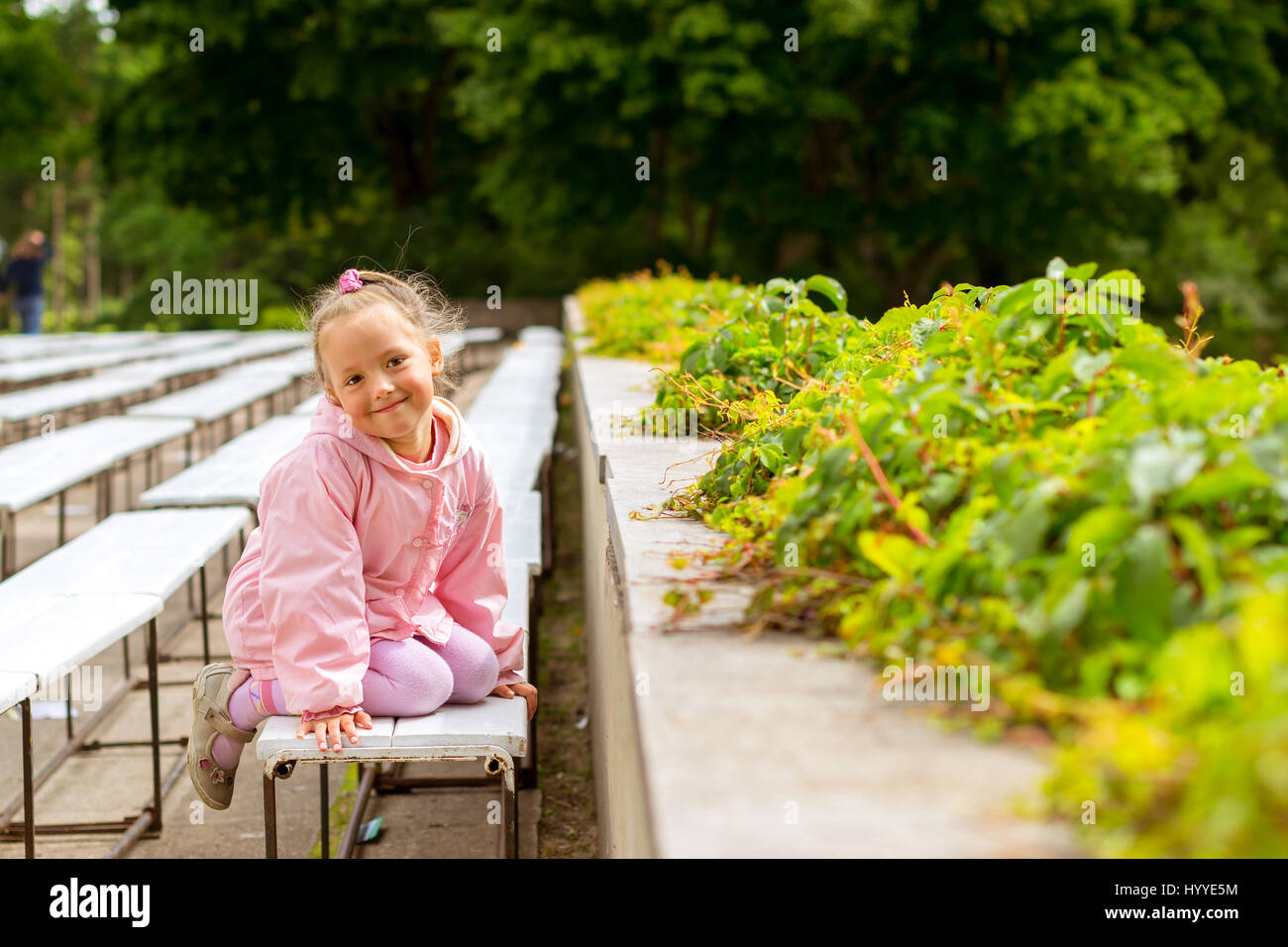 Cute little girl in a pink dress walks and plays in Palanga botanical ...
