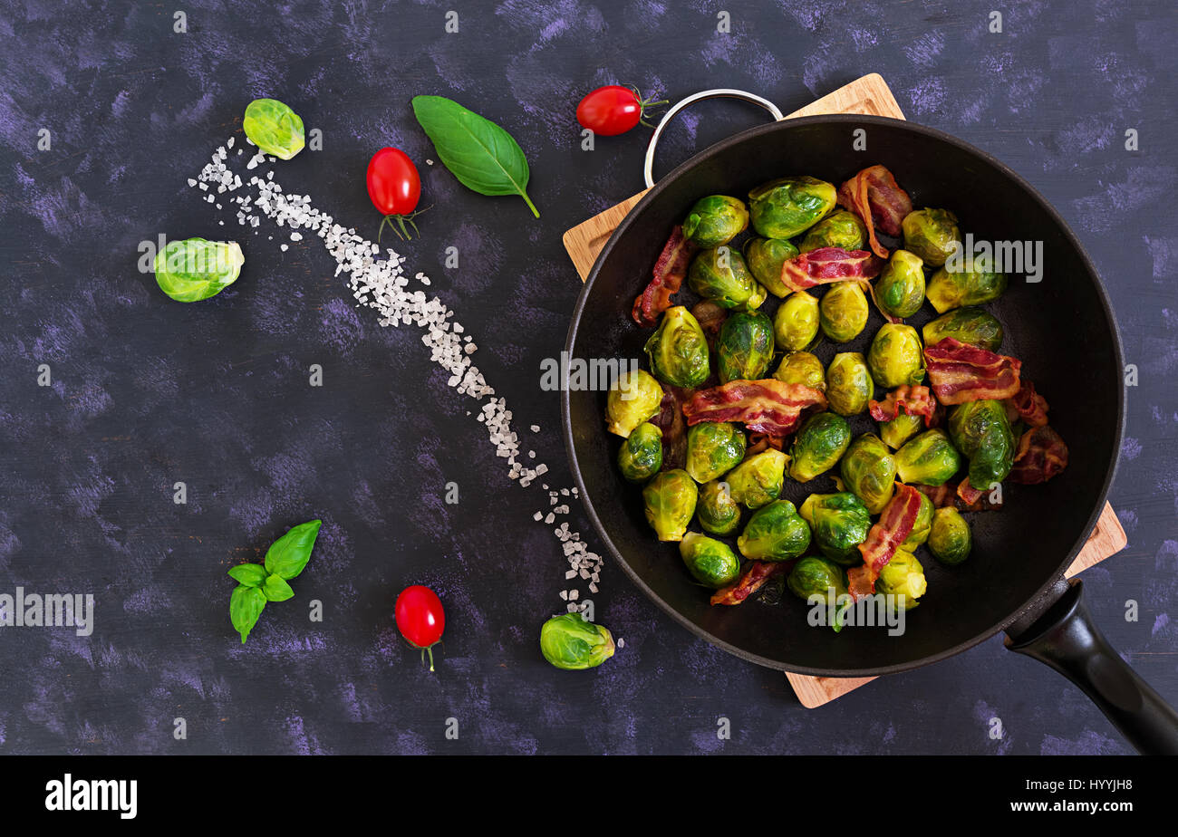 Roasted brussels sprouts with bacon on dark background. Top view Stock Photo