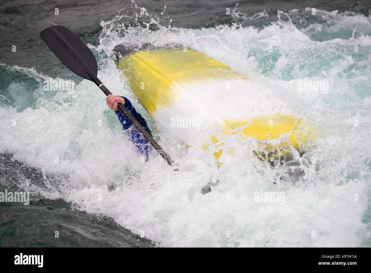 Capsized kayak boat on rough water, you can see an arm and paddle on
