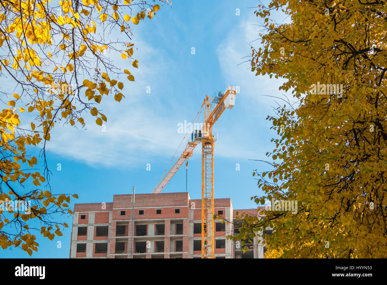 Crane and high-rise building under construction works against sun blue ...