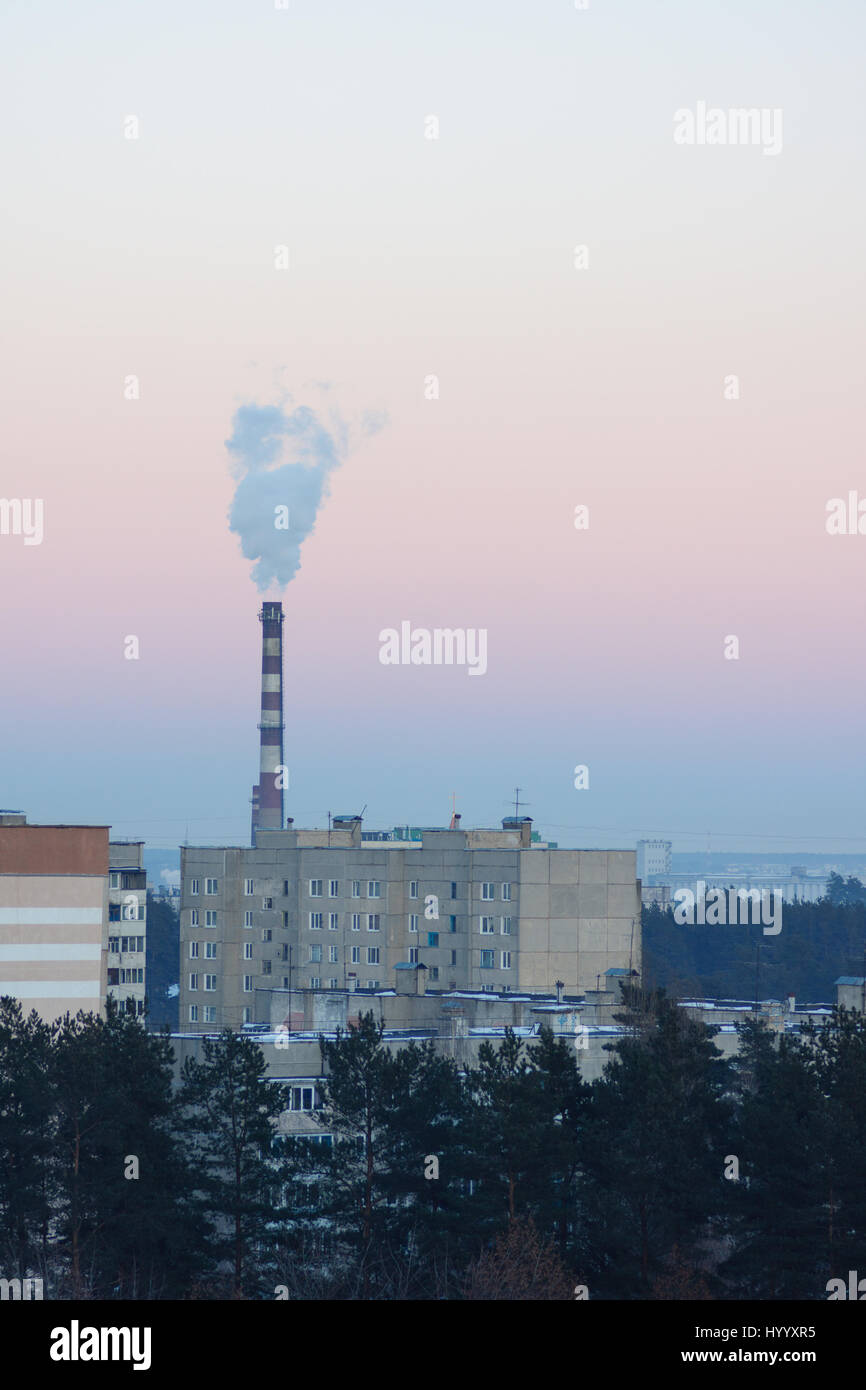 Fuming chimney over factory quarters in frosty air Stock Photo