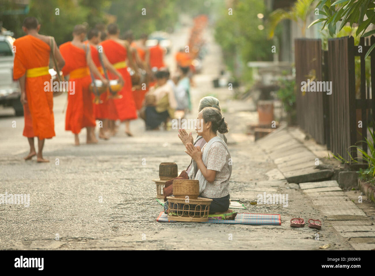 Lao People's Democratic Republic, Laos, Luang Prabang - 20 JUNE 2014: Woman prays after giving alms to buddhist monks on the street. Stock Photo
