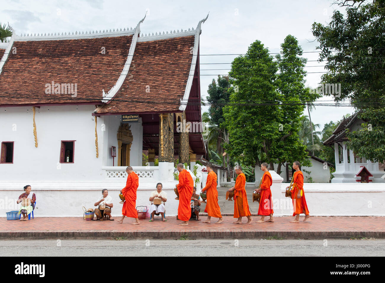 Luang Prabang, Laos - 22 June, 2014: Buddhist monks collecting alms from people on the street of Luang Prabang, Laos on 22 June, 2014. Stock Photo