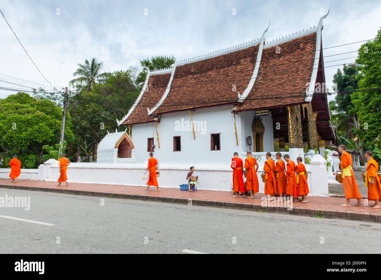 Luang Prabang, Laos - 22 June, 2014: Buddhist monks collecting alms from people on the street of Luang Prabang, Laos on 22 June, 2014. Stock Photo
