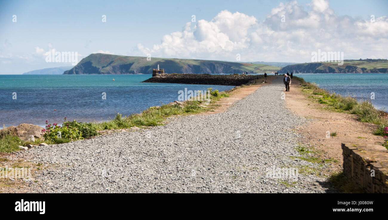 Fishguard, Wales, UK - May 21, 2009: Walkers stroll on the breakwater at Fishguard, with blue sea and the cliffs of the Pembrokeshire Coast. Stock Photo