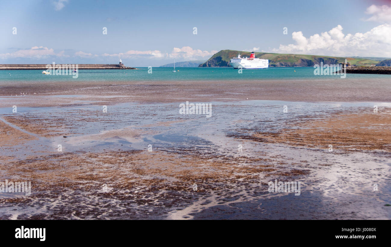 Fishguard, Wales, UK - May 21, 2009: A UK-Ireland ferry boat passes cliffs and beaches on the Pembrokeshire Coast as it enters the dock at Fishguard. Stock Photo