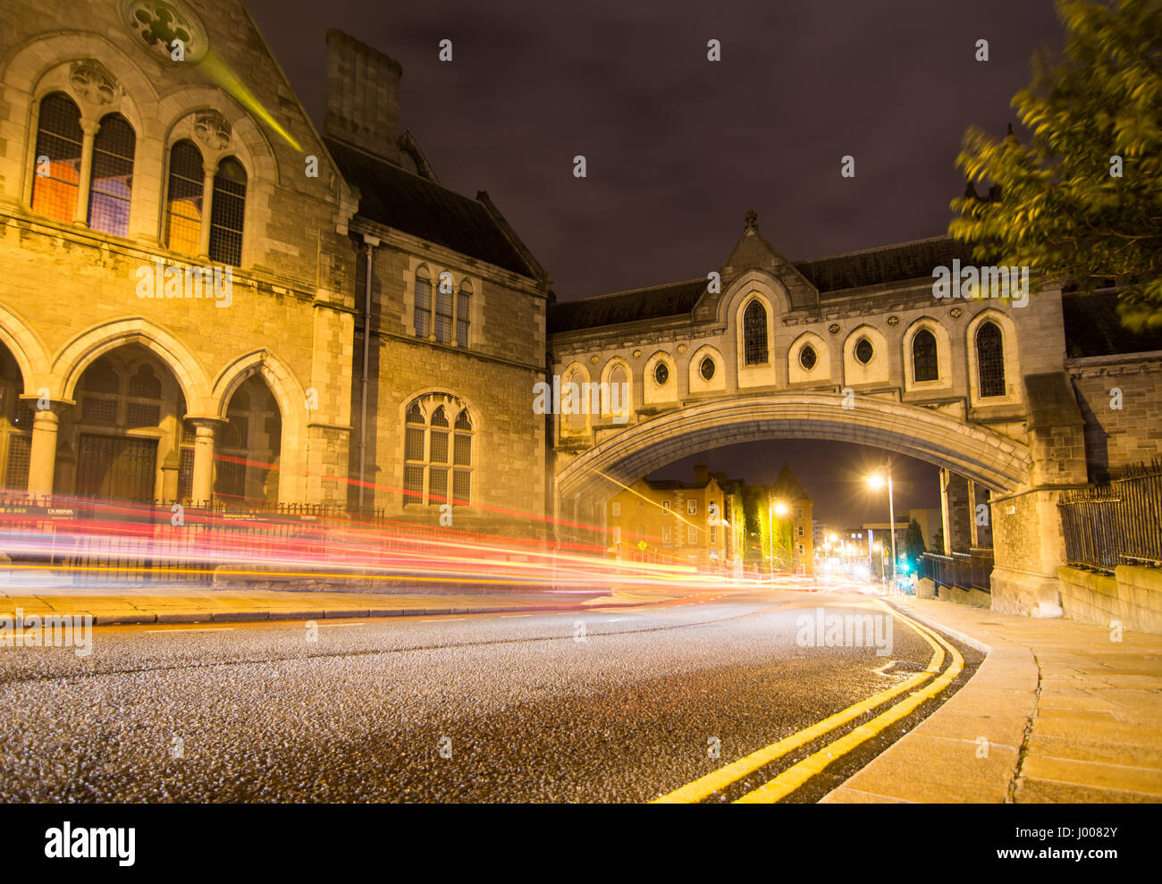 Traffic rushes down Winetavern Street in Dublin at night, under the enclosed stone arch bridge that links Christ Church Cathedral with the Synod Hall. Stock Photo