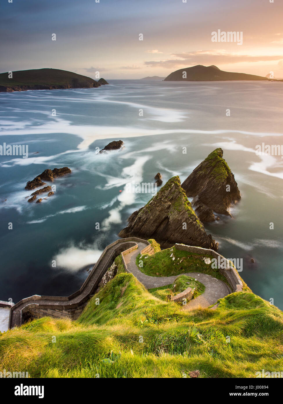 A narrow winding path leads down the cliffs at Dunquin on the Dingle Peninsula, in Ireland's County Kerry, with the Blasket Islands behind. Stock Photo