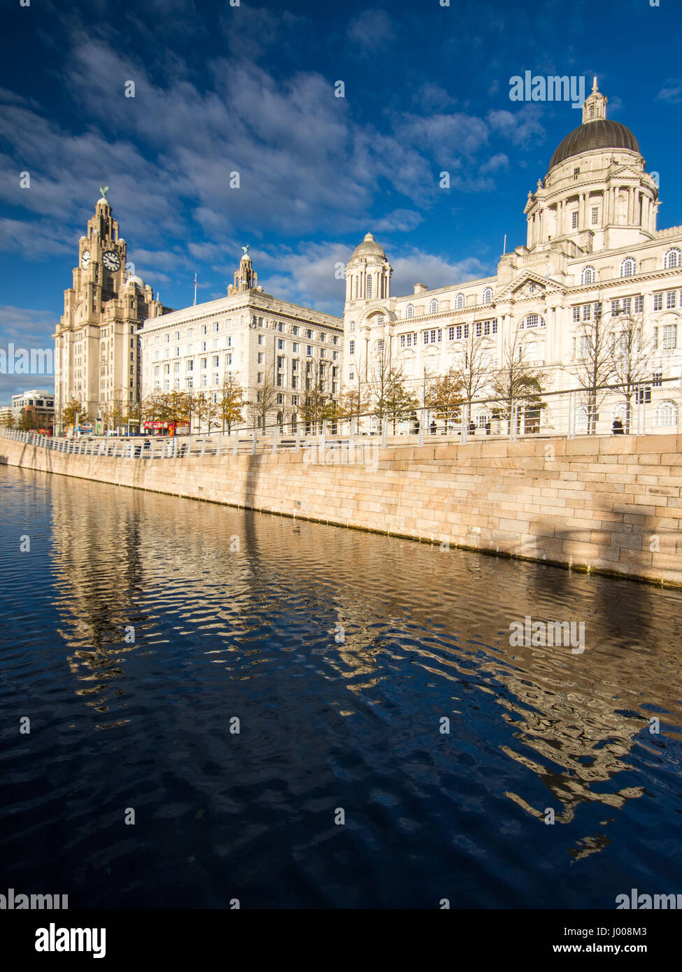 Sun shines on the iconic Liverpool docklands waterfront, with the Royal Liver, Cunard, and Port of Liverpool buildings. Stock Photo