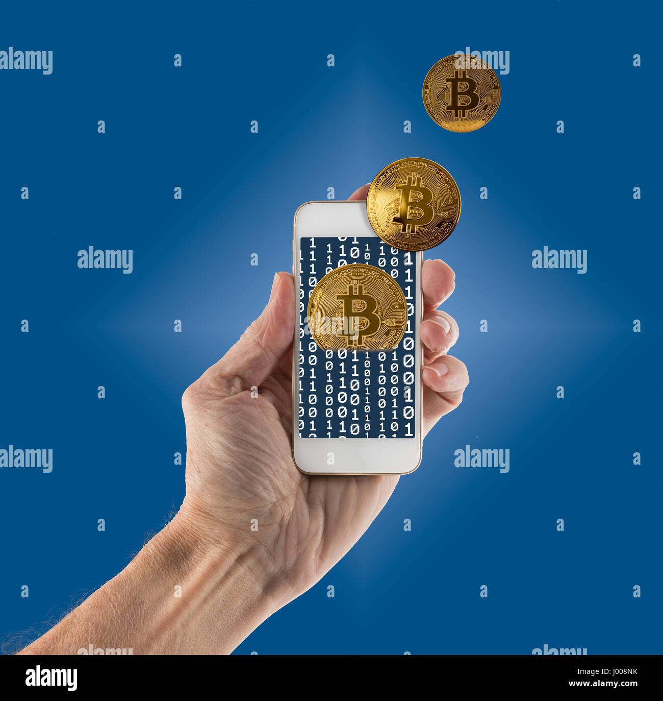 Bitcoins emerging from app on handheld smartphone Stock Photo