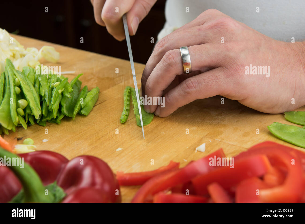 Close Up of Snow Peas Being Sliced on wooden butcher block Stock Photo
