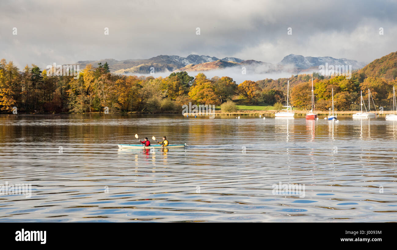 Two people paddle a canoe in Windermere lake at Ambleside, under the