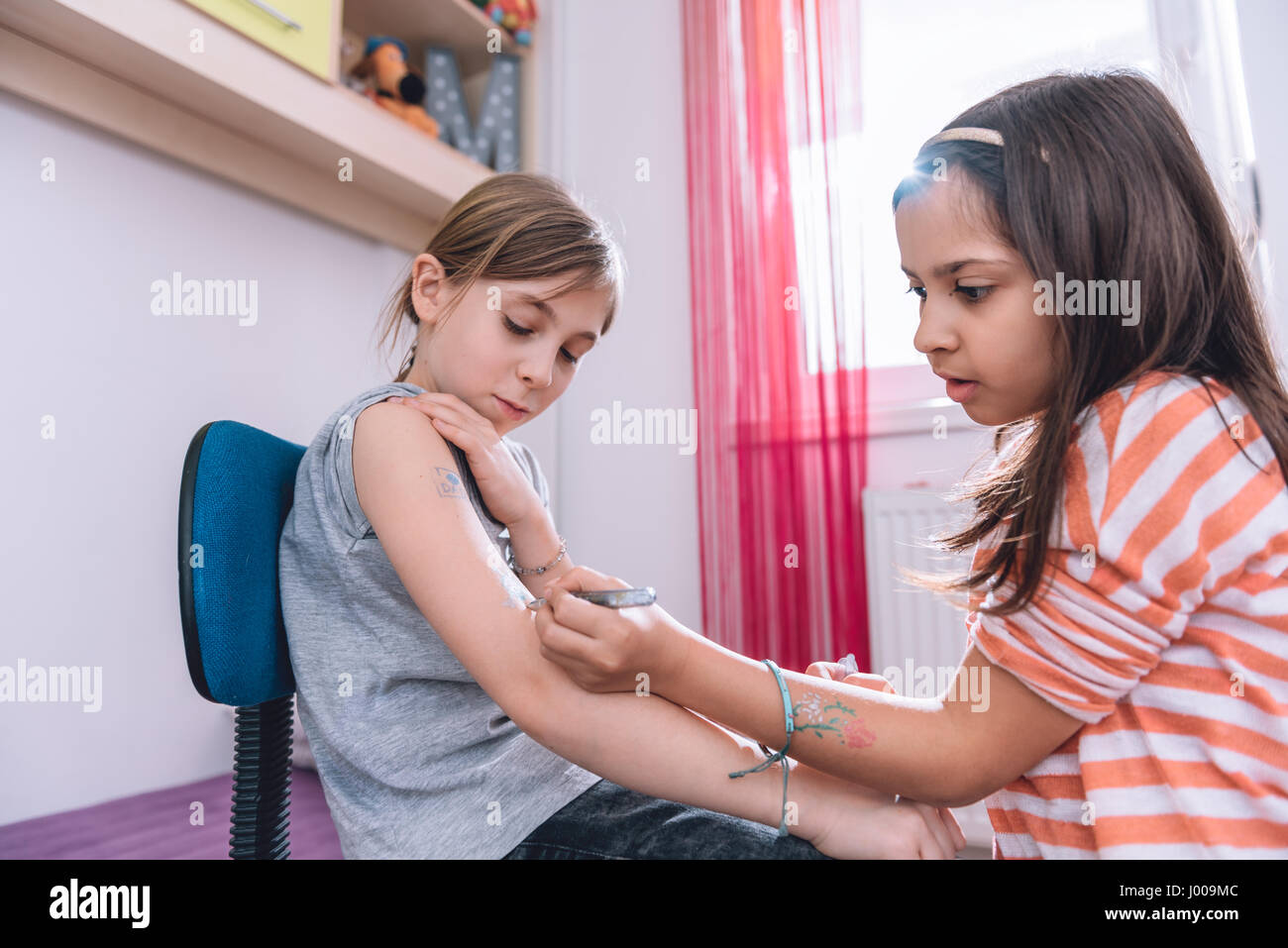 Girl writing tattoo on arm of her girlfriend with pen Stock Photo