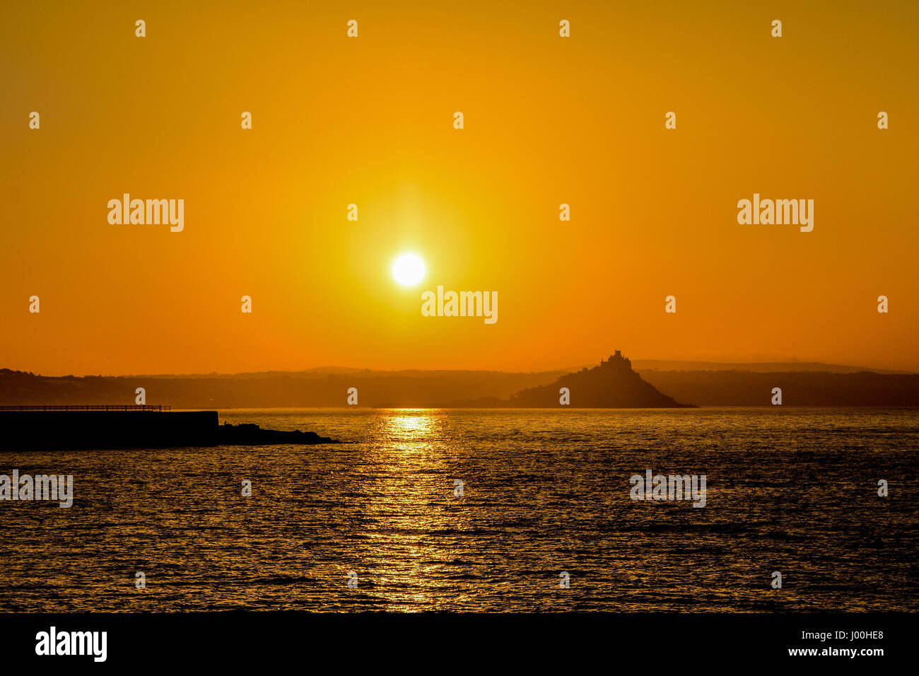 Penzance, Cornwall, UK. 8th Apr, 2017. UK Weather. The sun rises over Mounts Bay, and the Jubilee Pool - the outdoor Lido swimming pool, which has been closed for more refurbishment. Early morning haze lngered on the horizon, bringing a vivid orange glow around the sun. Credit: Simon Maycock/Alamy Live News Stock Photo